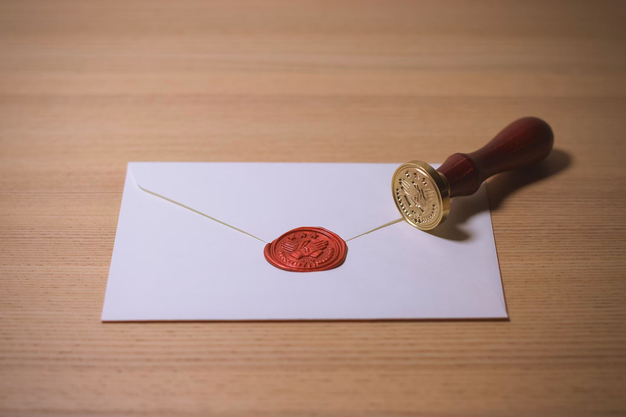 A white envelope with a red wax seal and the stamp that was used to make it